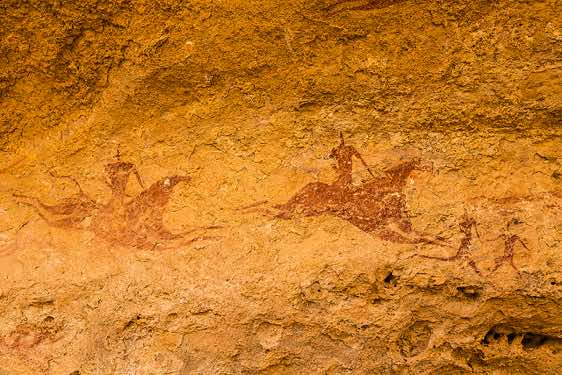 Prehistoric rock painting of galloping horses and riders behind two running figures, Terkei Cave, Ennedi Mountains, northeastern Chad