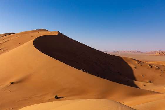 Hiking group climbing up a giant sand dune, desert landscape, Rub al Khali, Empty Quarter, Dhofar region