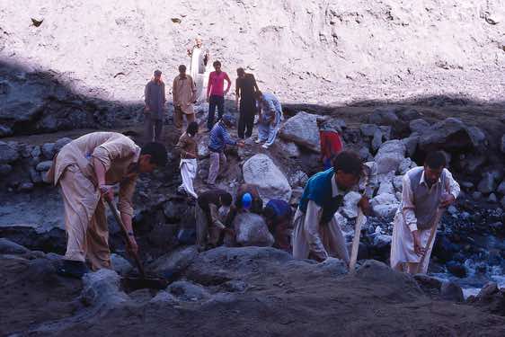 A group of porters is working hard to repair a section of the road that had been washed away, Karakoram Mountains