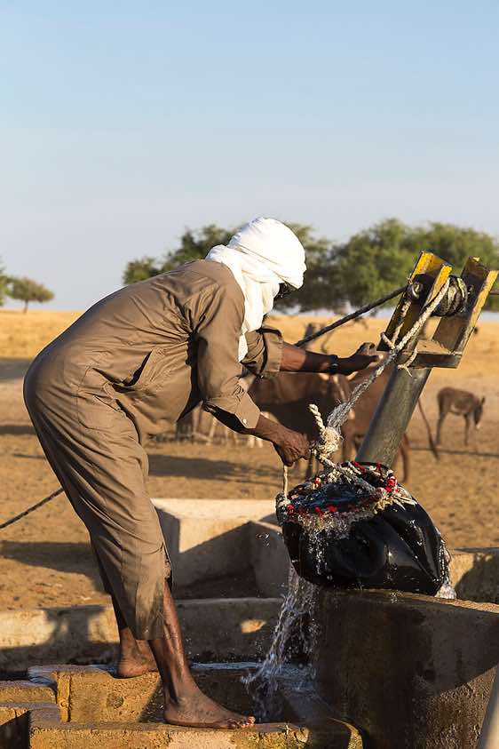 A nomad draws water from a well
