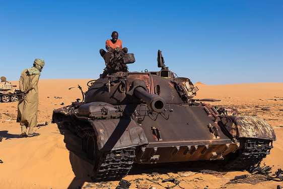 Driver Osman explores the remnants of a Libyan tank in the desert