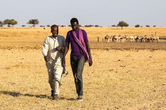 Driver Ibrahim and translator Moussa come back from a conversation with nomads at a well in the desert