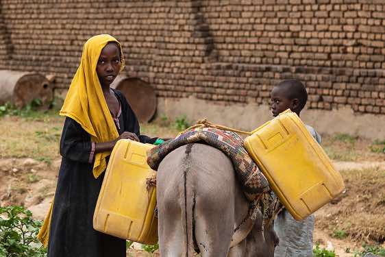 Girl fills up water canisters at a well, Abéché