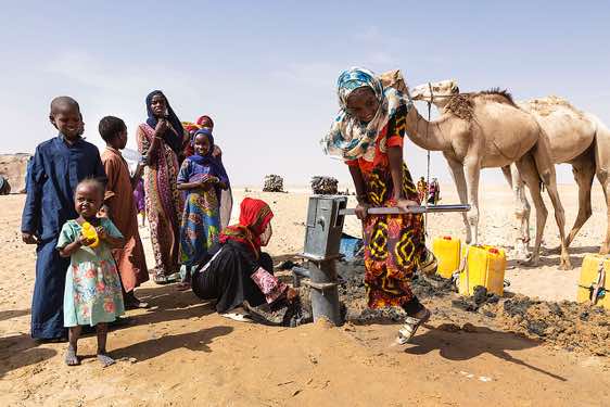 Girl pumping water at a well in the desert, Borkou region