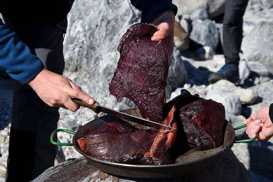 Preparing whale meat for dinner, campsite, Ikaasartivaq Strait