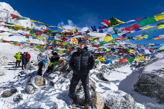 The photographer on top of Larkya La pass, 5100m, marked with colourful prayer flags