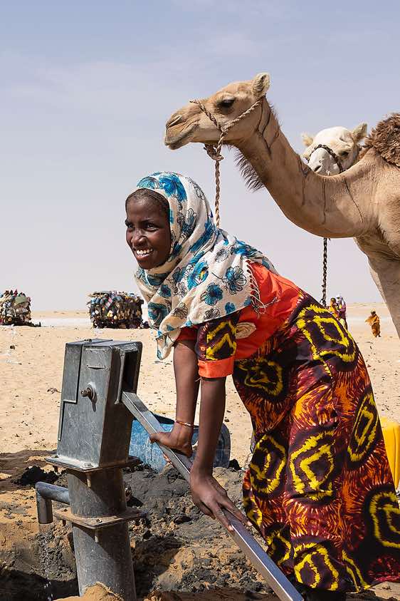 Girl pumping water at a well in the desert, Borkou region