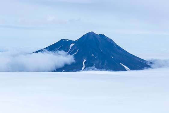 Summit of the Ilyinsky Volcano; the cone of the Zheltovsky Volcano rises from the sea of clouds, Kurile Lake