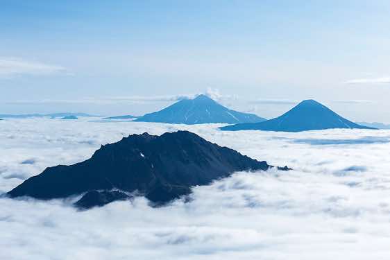 The cones of the Zheltovsky and Ilyinsky volcanos (background, from left) protrude from the sea of clouds, Pauzhetka area