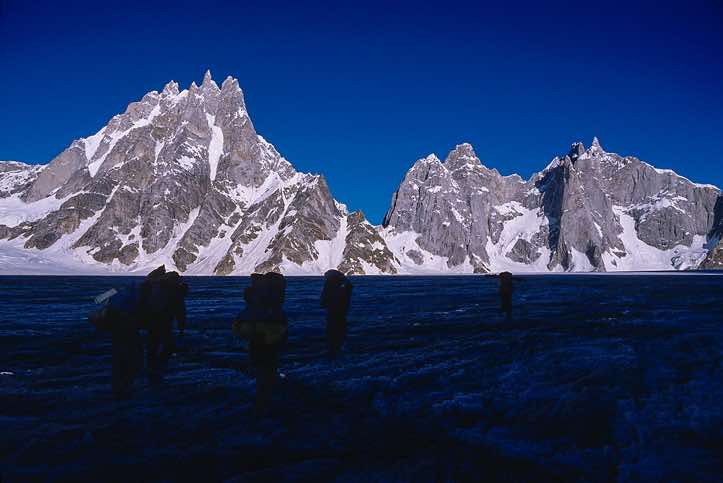 Group of porters on the Biafo Glacier with Sosbun Brakk, 6413m, and Broad Tower, 6066m, in the background, Karakoram Mountains