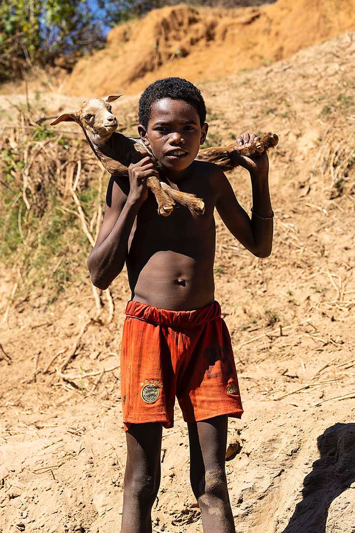 Young boy with a goat around his neck, Tsiribihina River, Western Madagascar