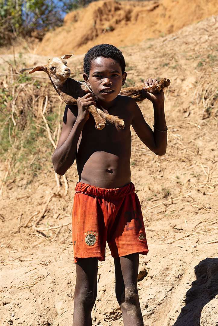Young boy with a goat around his neck, Tsiribihina River, Western Madagascar