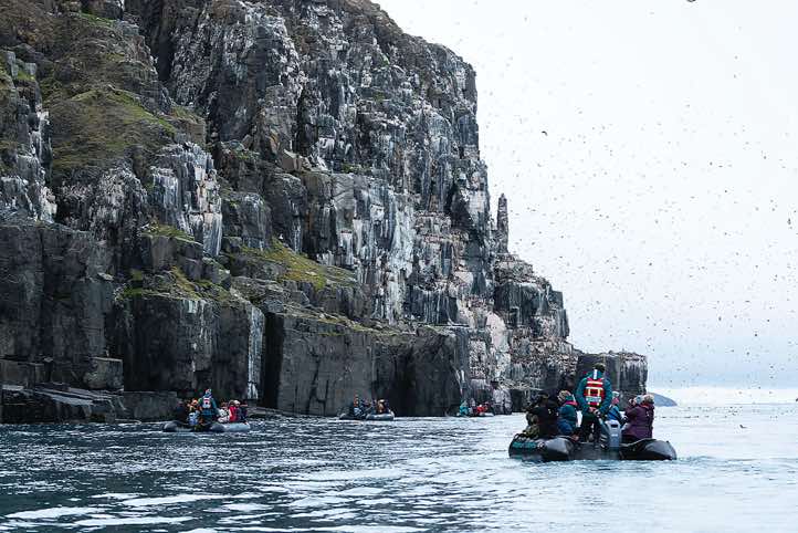 Zodiac cruising at Alkefjellet, a dramatic 100-meter-tall basalt bird cliff facing the Hinlopen Strait