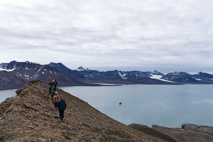 Hiking group walking along a mountain ridge between two glaciers, Valentinryggen, St. Jonsfjorden